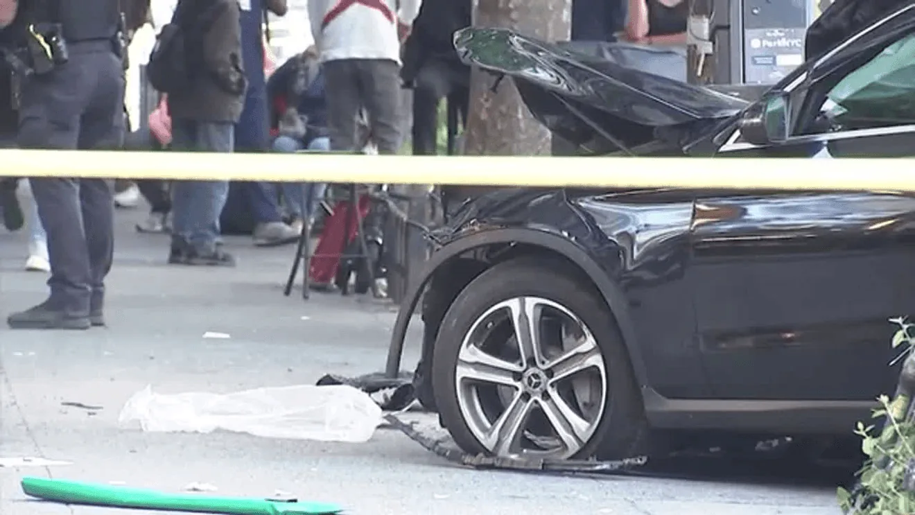 Police investigate a fatal crash scene in Manhattan near parked cars and a curb